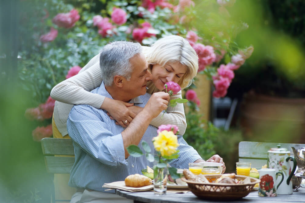 Seniorin duftet an Geranie aus dem Garten