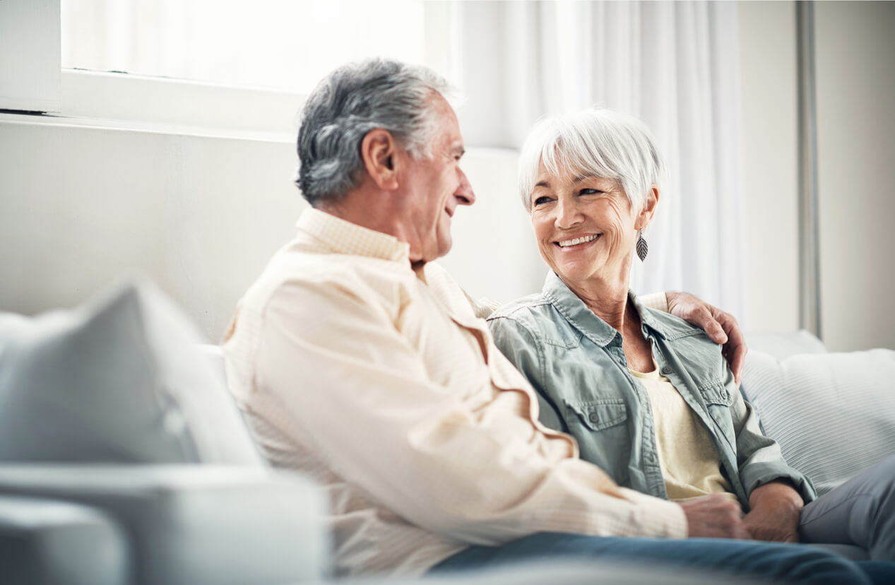Ehepaar sitzt auf dem Sofa und lächelt sich an